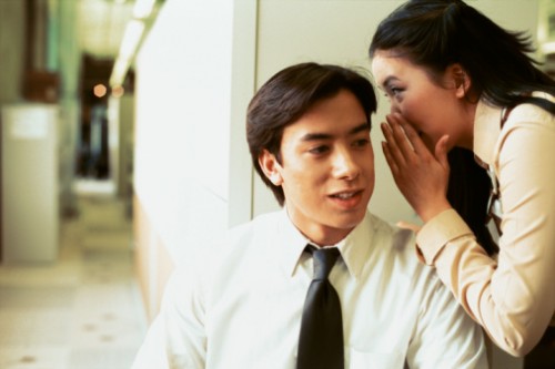A woman whispering into a man's ear