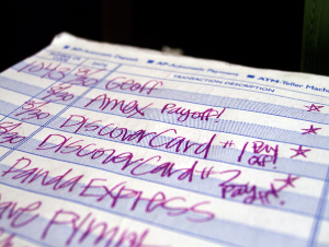 Close-up of a checkbook register that reflects multiple credit card payments, including one marked “payoff.”