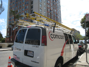comcast_internet_essentials A Comcast service van is parked on a city street.