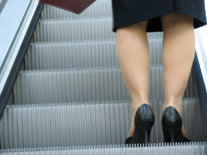 how_to_get_ahead_at_work Rear close-up of a businesswoman's pump-laden heels as she ascends and escalator.