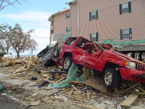 The aftermath of a very expensive natural disaster. Buildings and cars in the street show signs of ruin.