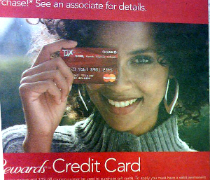 Close-up of a smiling woman in an advertisement who is holding a credit card in front of her right eye.