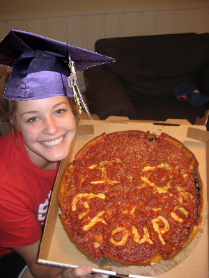 A college student shows off a pizza with the words “I (heart) Groupon” written in the sauce.