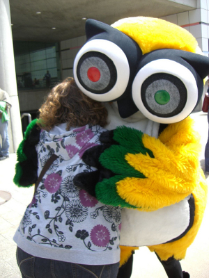 The TripAdvisor logo owl mascot gives a woman a hug.