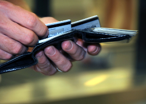 Close-up of a consumer's hands examining various credit cards in a wallet.