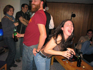 A man and a woman share drunken butt-to-butt laughs at a party. Image Title: drunk