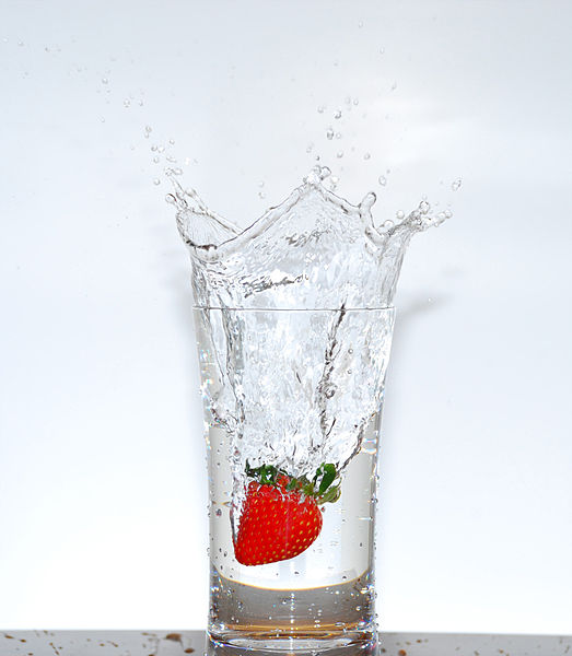 flavored_water A strawberry is dropped into a glass of water, sending a splash into the air.