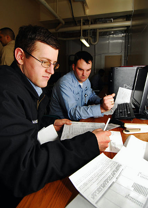 A U.S. Navy tax professional helps a corpsman complete his tax return.