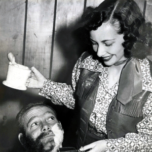 Retro 1950s photo of a woman giving a man a shave.