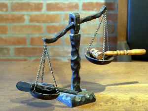 The scales of justice, showing that the gun holds weight over the judge's gavel.