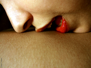 Close-up of a woman's lips kissing a torso.