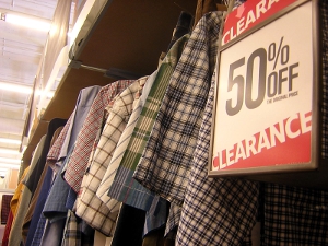 Close-up of a 50 percent off clearance sign next to a clothing rack.