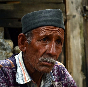 An elderly man gazes on with furrowed brow.