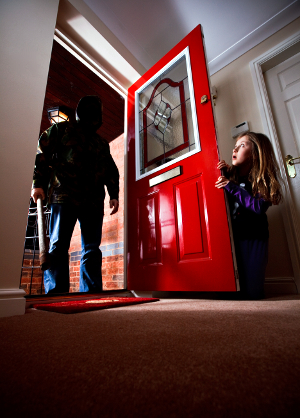 debt_collection A woman hides behind her open front door as a menacing figure stands before her, ready to enter.