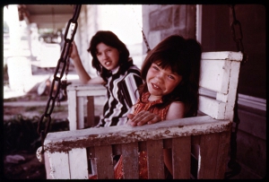 U.S. archival photo of siblings in an wooden porch swing.