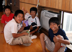 Four Japanese boys show their appreciation for the newly installed air conditioning units at the Arahama Community Center. The center received six window units, courtesy of a joint effort between the U.S. military and Japan Self-Defense Forces. Fifteen Seabees from Naval Air Facility Atsugi were sent to help in the effort to the area still reeling from the effects of a July 16 earthquake. The quake killed 10, left more than 1,200 injured, destroyed nearly 1,000 homes and damaged 4,000 others.
