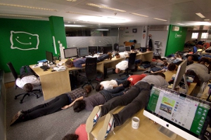 Office employees planking on their desks and on the floor.
