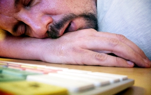 A male worker falls asleep at his desk.