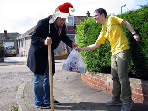 random_acts_of_kindness Young man helping an old man in a Santa Claus hat.