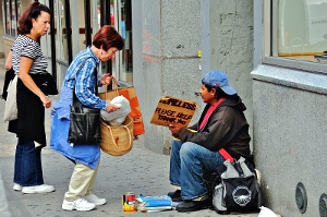 alternative_ways_to_support_charity Women giving bagged goods to a homeless man sitting on a sidewalk.