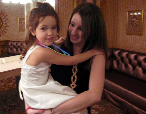 A teenaged female babysitter holding a young girl.