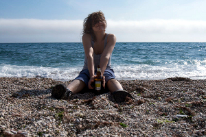 new_year's_resolutions A happy young woman seated on a beach.