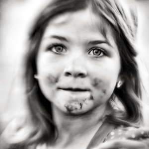 Black-and-white photo of a little girl with chocolate smudges around her mouth.