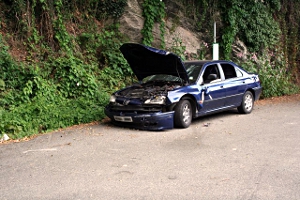 A wrecked, broken-down car at the side of the road.