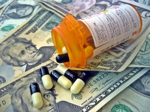 An open pill bottle spilled across a bed of $20 bills.