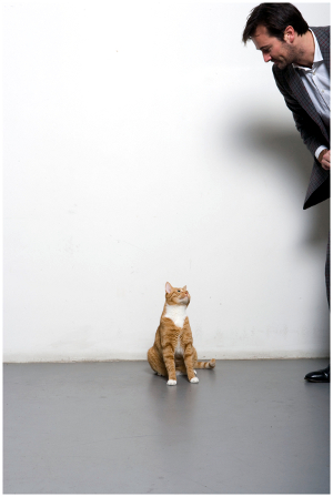 A man having a staring contest with a cat.