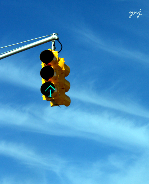 A traffic signal with a green arrow that points upward.