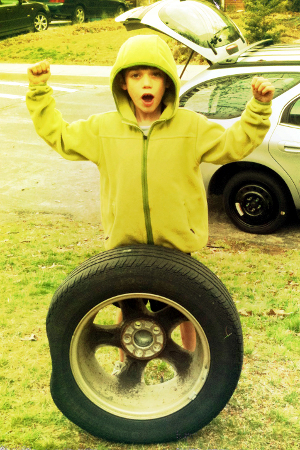 A boy changing a spare tire.